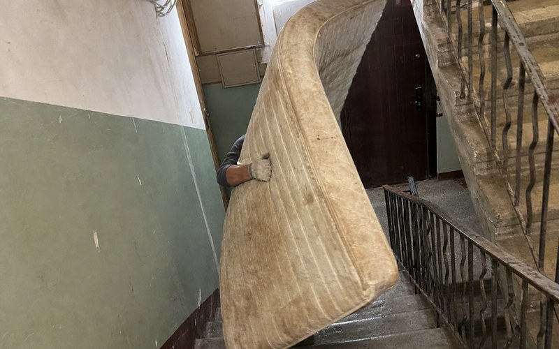 An old double mattress being carried down a narrow stairwell