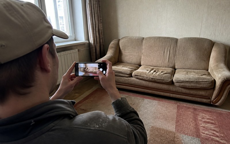 A customer photographing an old sofa with a phone to get a price